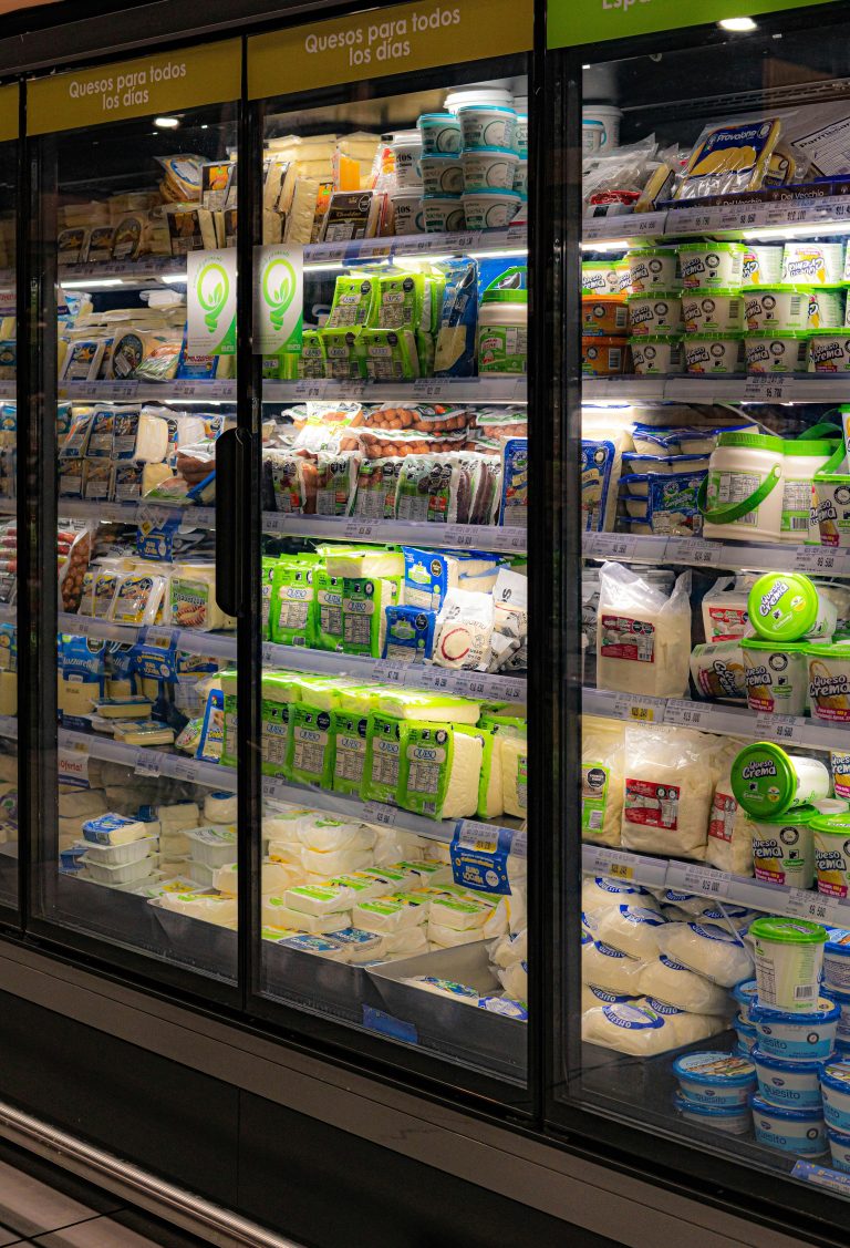 Commercial fridge full of various plastic packaged items.